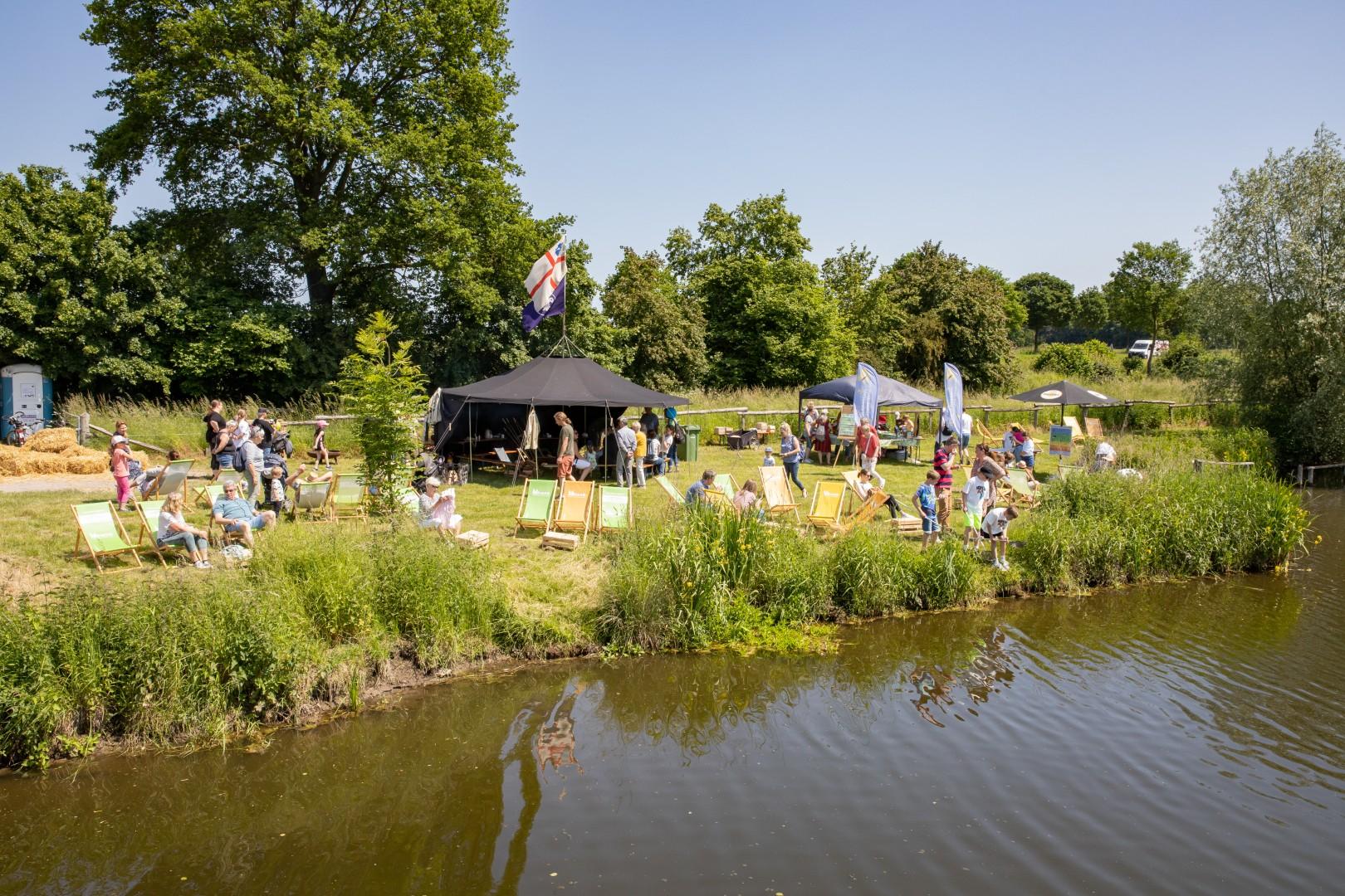 Besucher und Stände bei sonnigem Wetter am Floßanleger.
