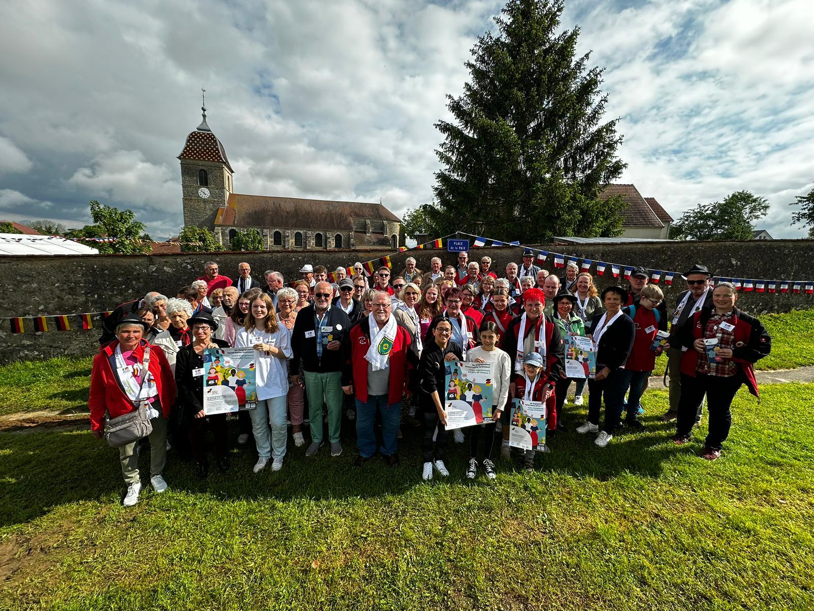 Auf dem Foto sind die Gastgeber und Gäste auf dem Platz des Friedens in Velesmes zu sehen. Im Hintergrund erkennt man die Kirche.