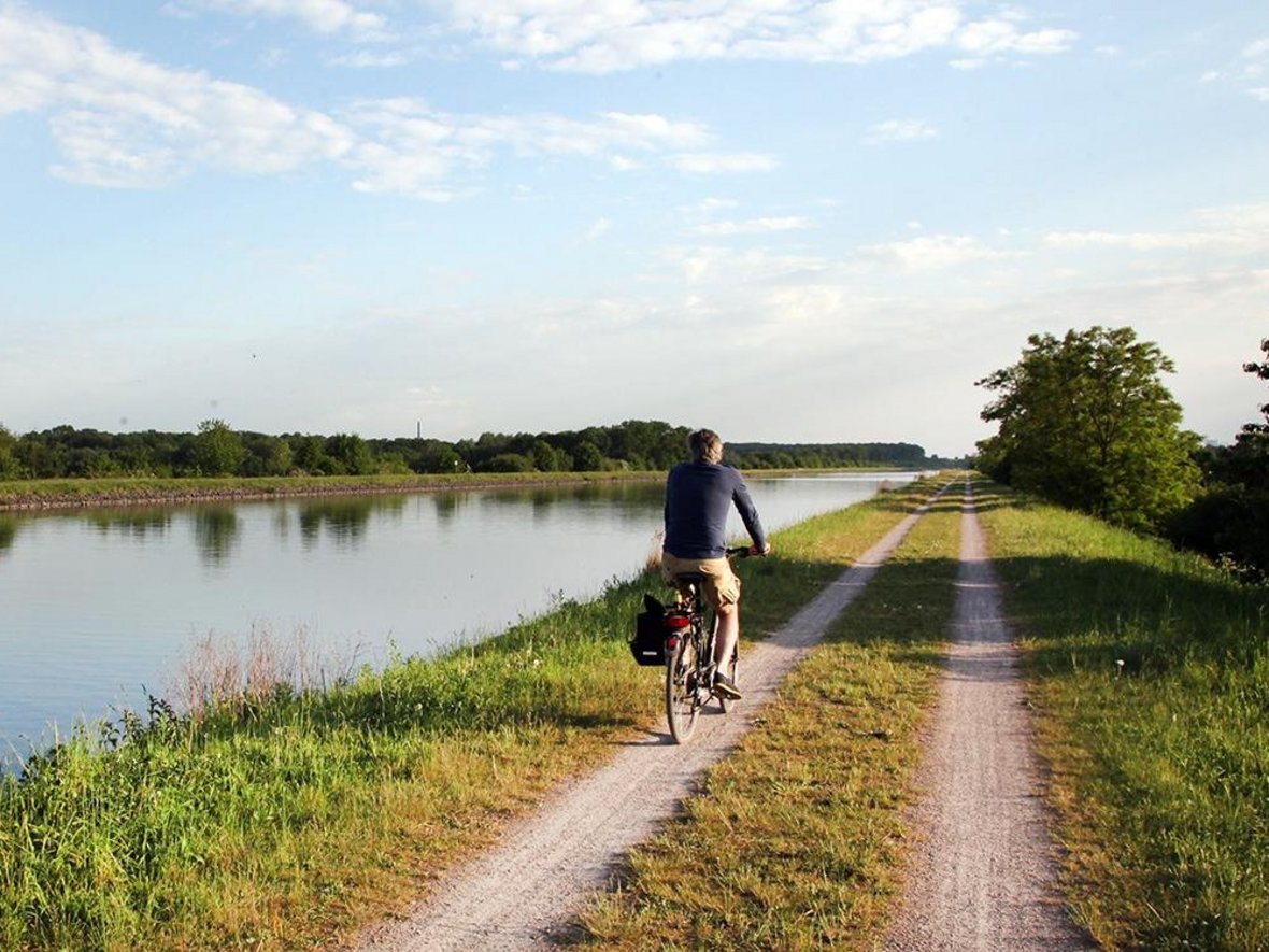 Ein Radfahrer fährt auf dem Schotterweg direkt entlang am Dortmund-Ems-Kanal.