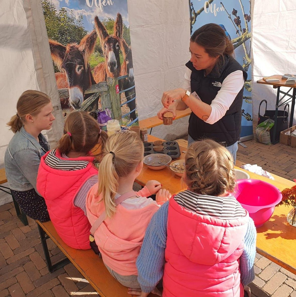 Eva Beckmann, die Klimaschutzbeauftragte der Stadt Olfen, erklärt vier Kindern beim Naturparktag, wie man Vogelfutter herstellt.