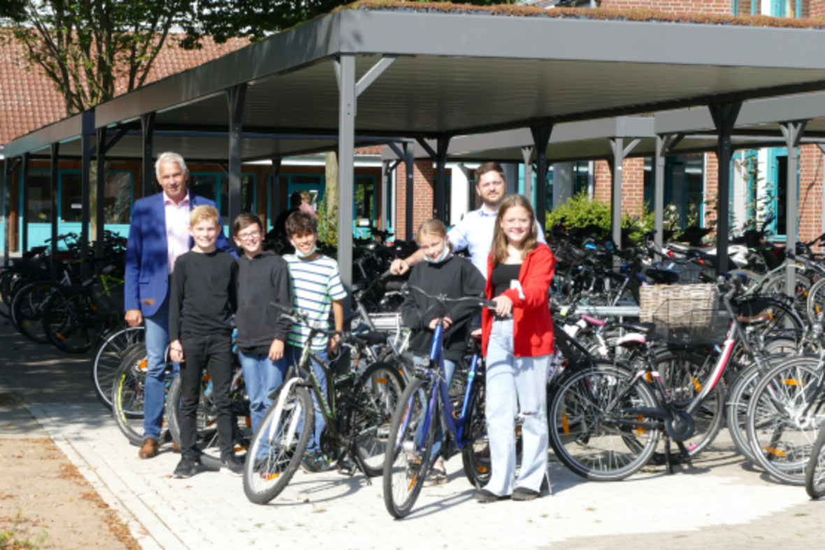 Bürgermeister Sendermann und fünf Schülerinnen und Schüler der Wolfhelmschule stehen vor der neu errichtete Fahrrad-Abstellanlage.