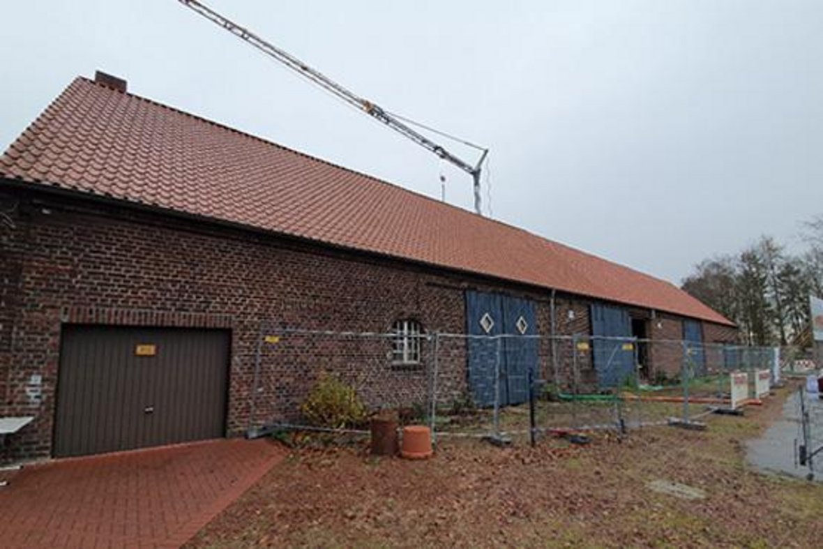 Auf dem Foto ist die Scheune, die heute das Naturparkhaus Steveraue ist, vor dem Umbau zu sehen. Sie sieht aus wie eine alte landwirtschaftlich genutzte Scheune mit großen blauen Toren.