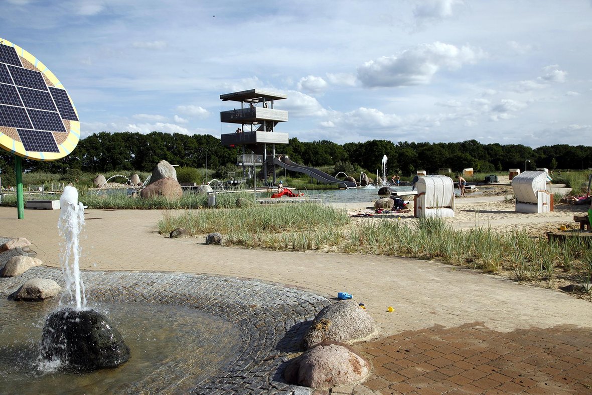 Auf dem Foto sieht man das Babybecken des Naturbades. Im Hintergrund ist der Sprung- und Aussichtsturm des Naturbades sowie das Schwimmbecken zu erkennen.