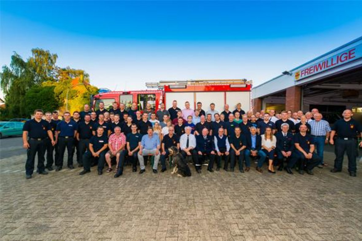 Hier ist ein Mannschaftsfoto der freiwilligen Feuerwehr Olfen zu sehen. Im Hintergrund steht ein Einsatzwagen der Feuerwehr.