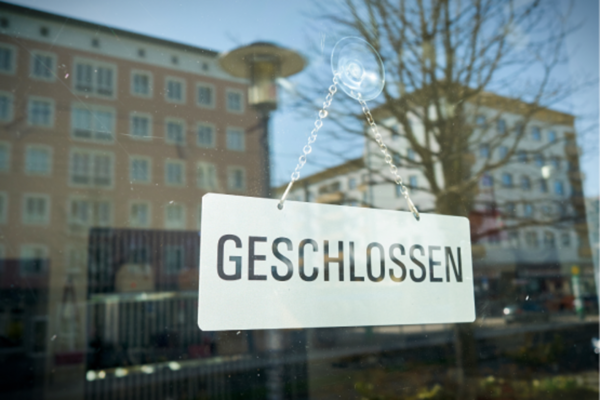 Auf dem Bild erkennt man ein Schaufenster hinter dem ein Schild mit der Aufschrift GESCHLOSSEN. Das Bild symbolisiert den Leerstand im Einzelhandel.