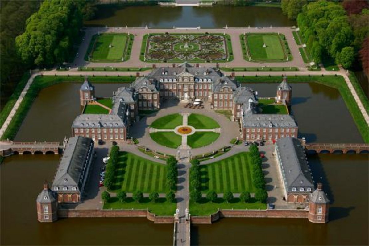 Das Foto zeigt eine Luftaufnahme vom Schloss Nordkirchen. Die große Anlage, historischen Bauten und das Wasser drum herum sind deutlich zu erkennen.