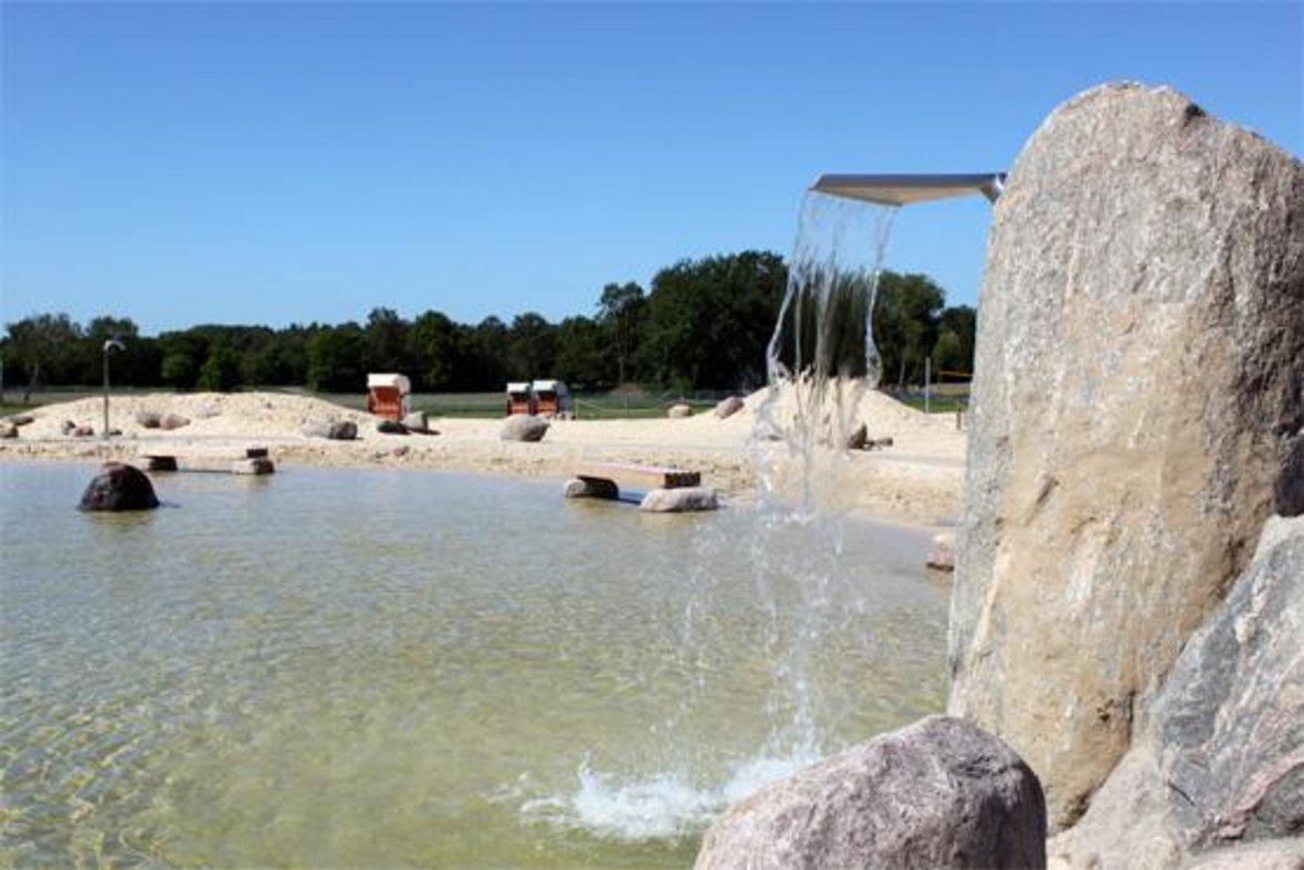 Hier ist der Strand- und Nichtschwimmerbereich des Naturbades zu sehen. Das Wasser ist klar.