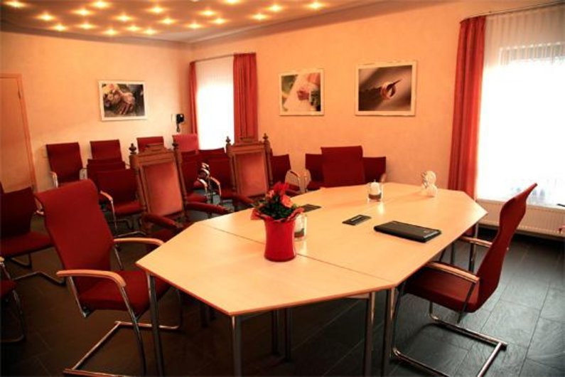 Das Trauzimmer im Bürgerhaus hat leicht orangefarbene Wände und rote Stühle.