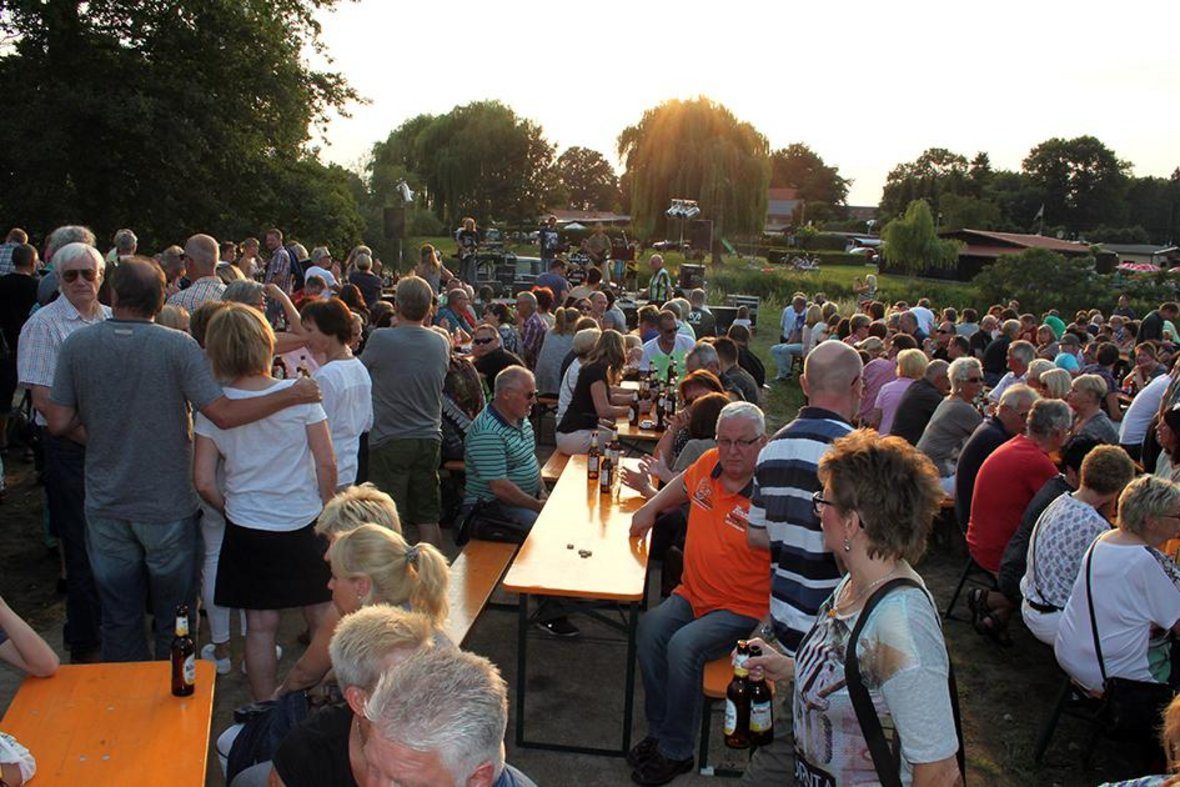 Das Foto zeigt hunderte Besucher auf einem der Summer Specials an der Füchtelner Mühle. Sie sitzen an Tischen, reden miteinander. Im Hintergrund ist die Band auf der Bühne zu sehen.