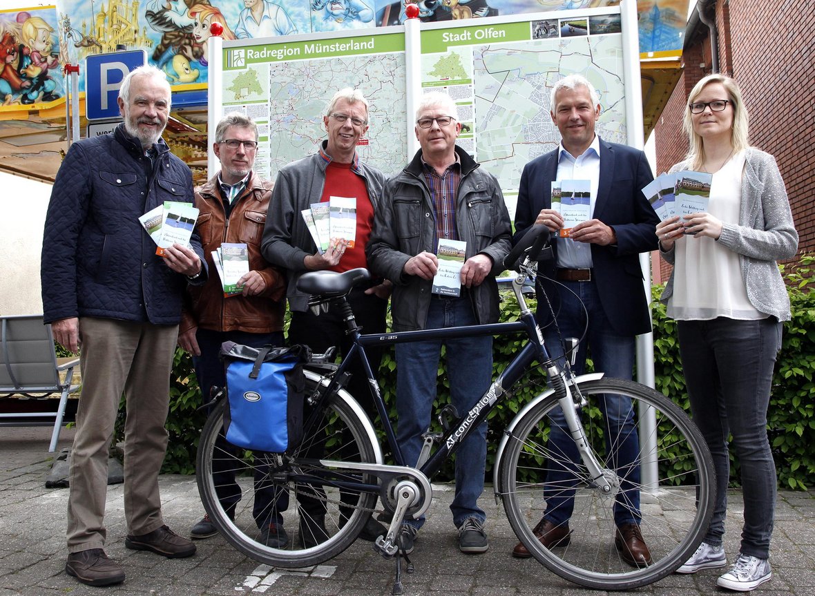 Mitglieder der SuS Radlertreffs halten die Flyer für die vier Radrouten in die Nachbarstädte in den Händen und stehen vor dem Park+Bike Platz am Rathaus.