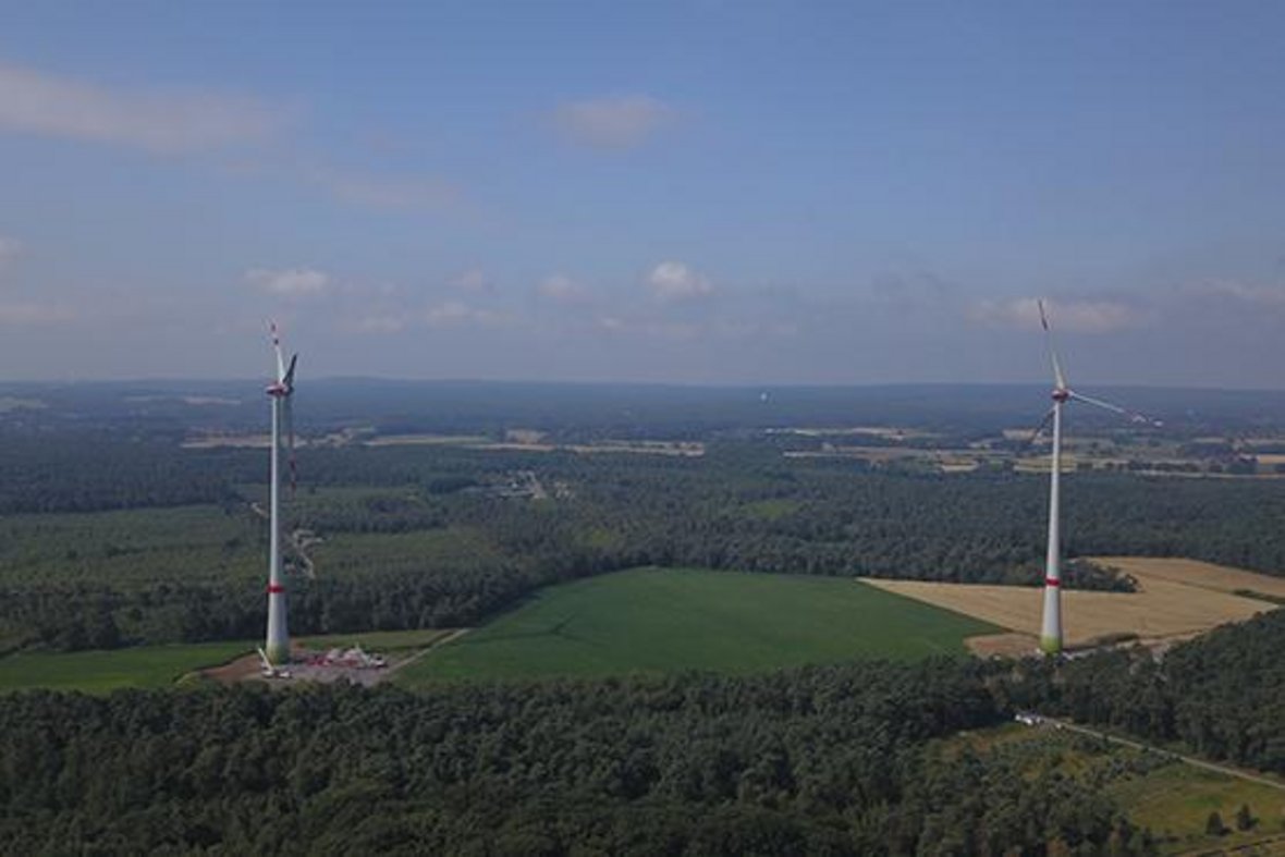 Das Luftbild zeigt zwei Windräder im ländlichen Raum.