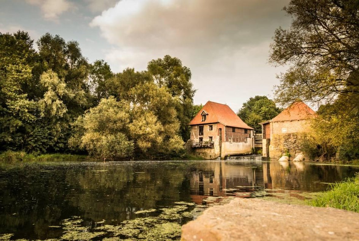 Im Hintergrund sieht man die Füchtelner Mühle. Davor die Stever und der dortliegende sandige Flussstrand.