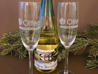 Zwei Sektgläser mit der Aufschrift "Ein gutes SCHLÜCKchen Münsterland" sowie der Sekt Olfens Steverperle werden auf diesem Bild präsentiert.