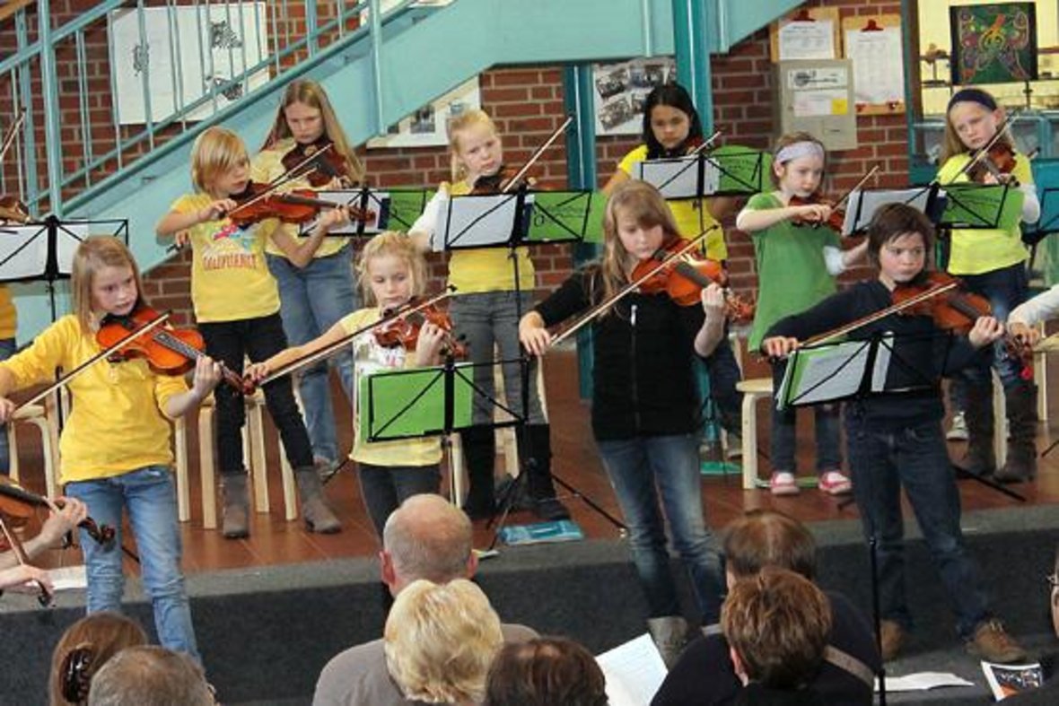 Die Big Band der Gesamtschule Olfen spielt in der Aula der Gesamtschule Musik. Viele Kinder spiele Geige.