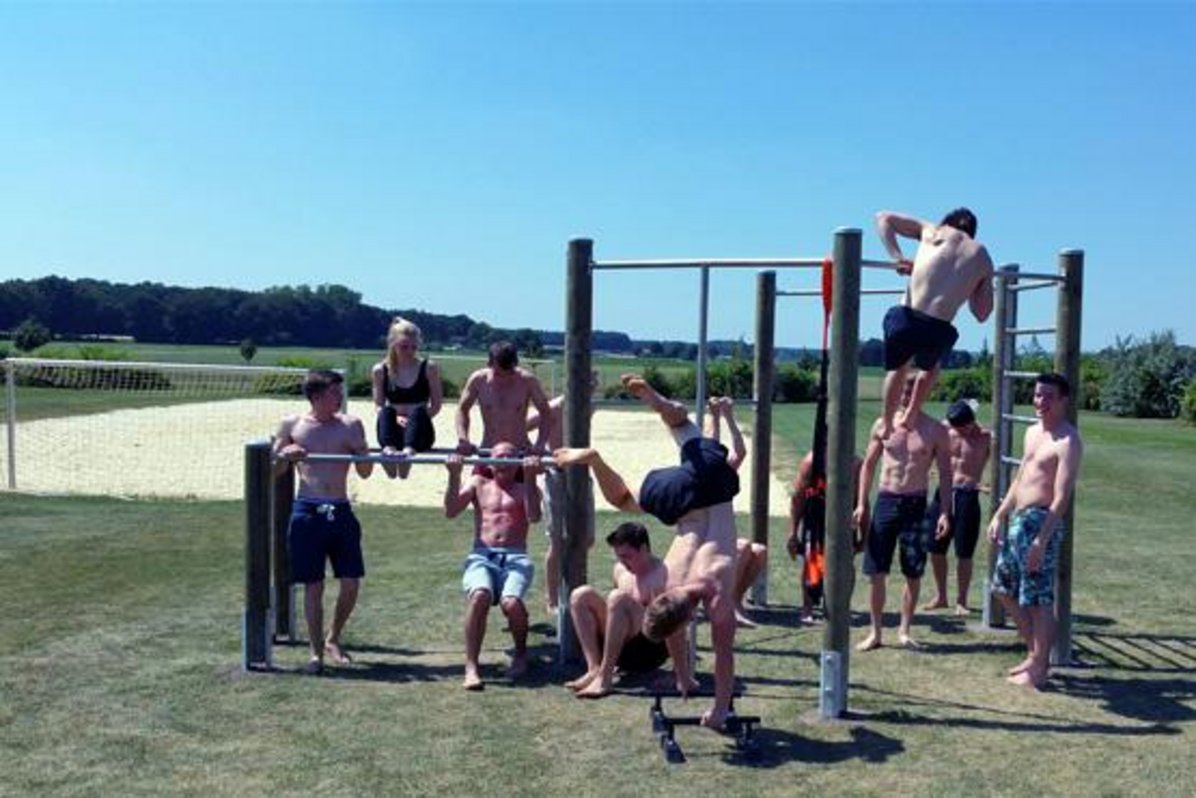 Viele Jugendliche stehen an der Calisthenics-Anlage im Naturbad. Verschiedene Turnstangen sind dort für den Sport angeracht worden.