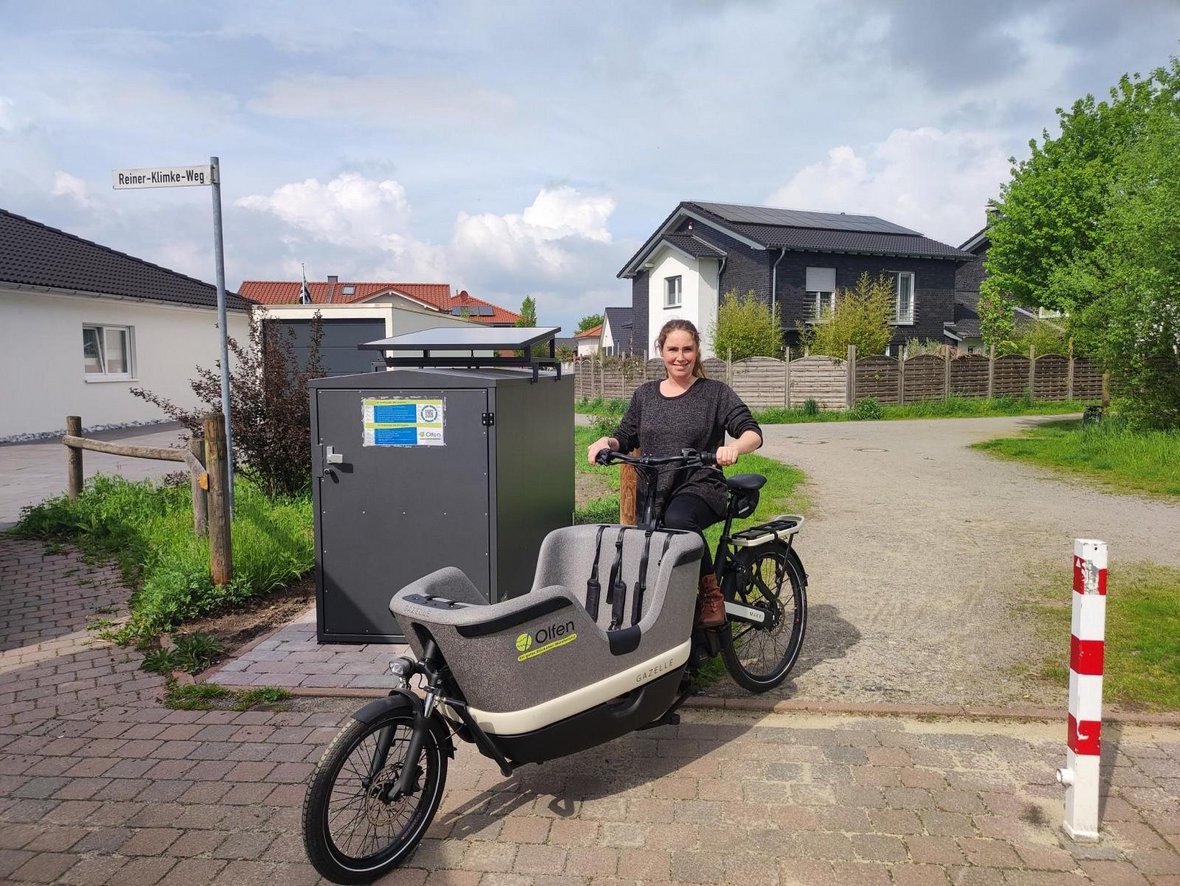 Das Bild zeigt eine Frau, die auf einem Lastenrad der Stadt Olfen sitzt.