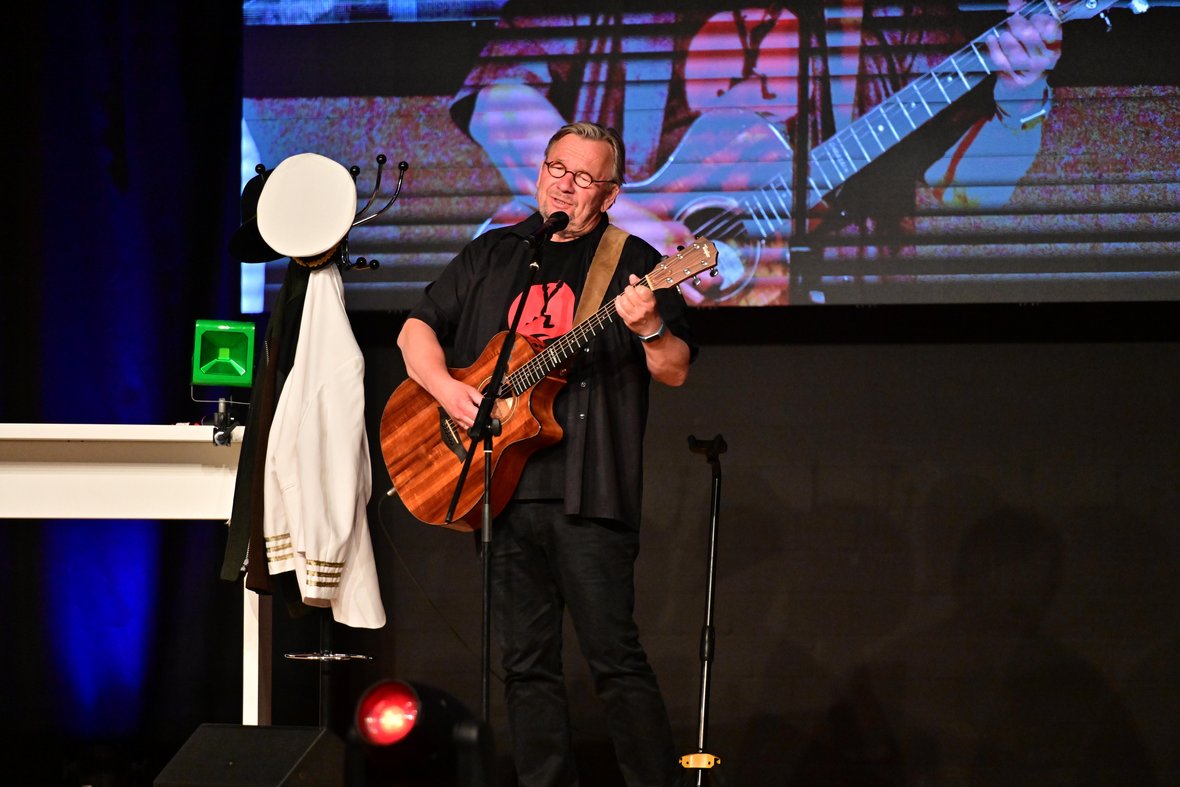 Bernd Stelter steht auf der Bühne in der Stadthalle Olfen und spielt Gitatrre.