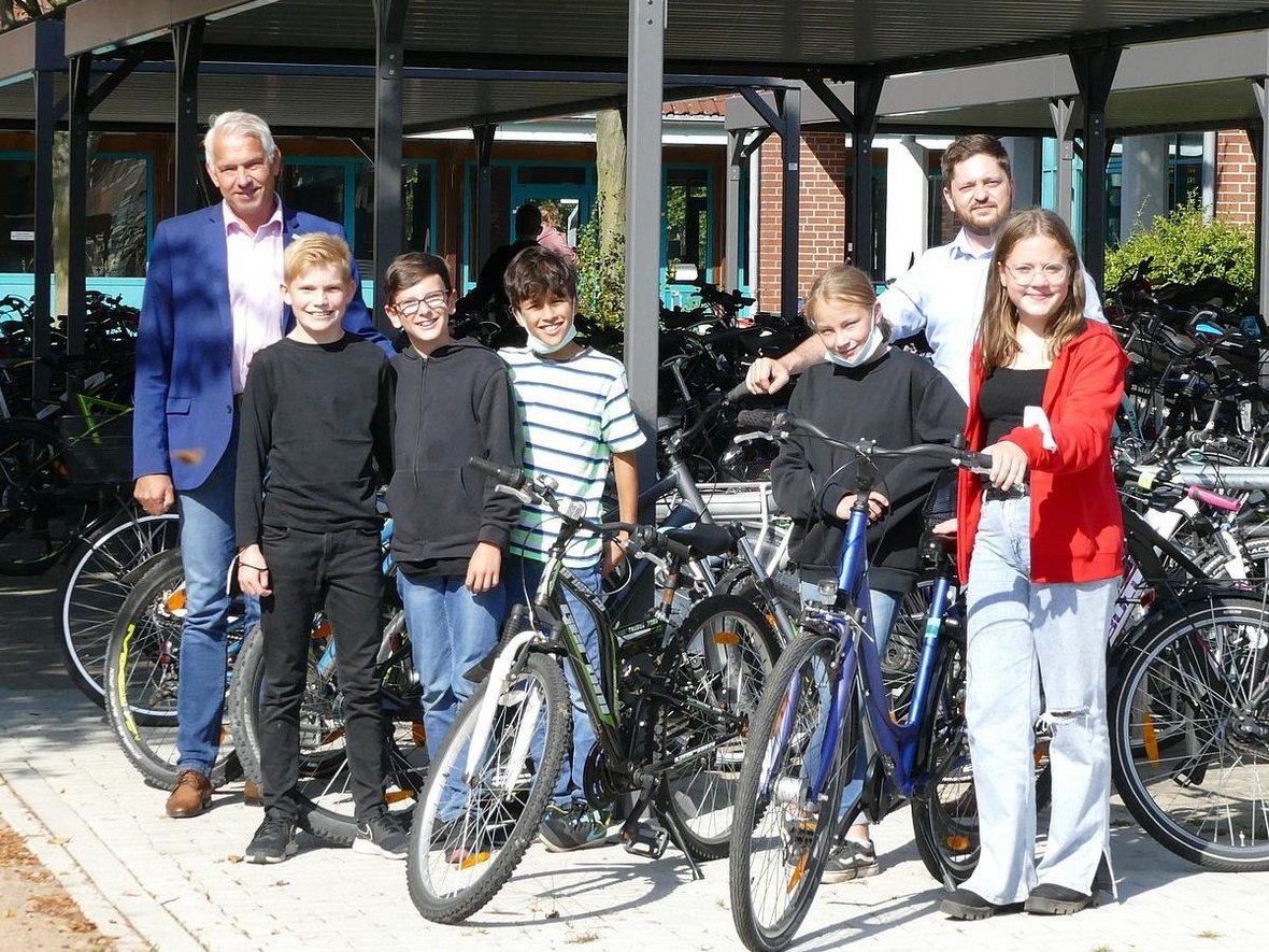 Bürgermeister Wilhelm Sendermann steht mit fünf Schülerinnen und Schülern der Wolfhelmschule vor den neu errichteten Fahrrad-Abstellanlagen.